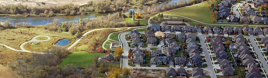 Aerial of a neighborhood with homes beside a river.
