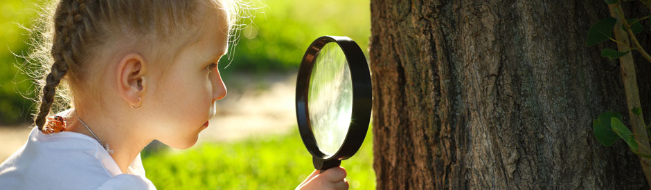 Girl looking at tree through magnifying glass