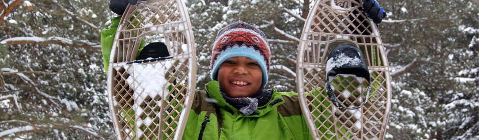 Smiling boy holding snowshoes