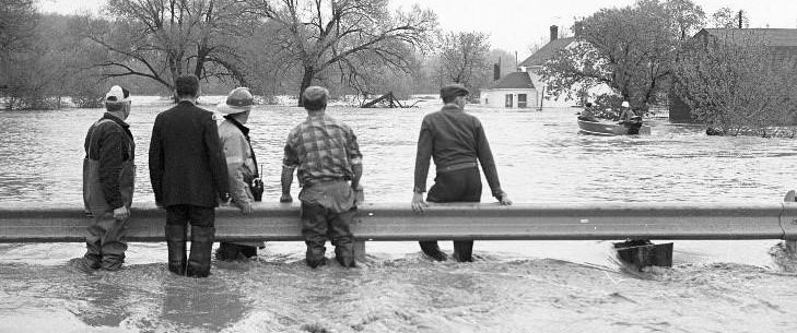Group of people standing in moving flood waters, Bridgeport, during the flood of 1974