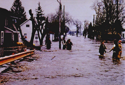 Residents standing in flooded street in residential area, Bridgeport, during flood of 1974