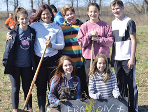 Susan Frasson and family standing behind a sign while planting trees in Guelph
