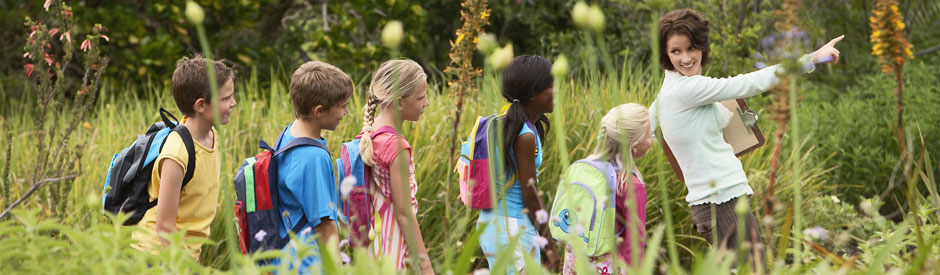 School group outside in nature being led by a teacher