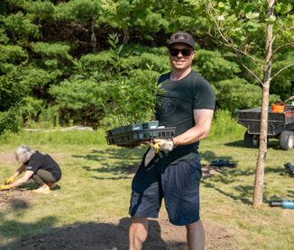 A volunteer carries a tray of native plants and a trowel while helping plant the Indigenous Garden at the Guelph Lake Nature Centre.